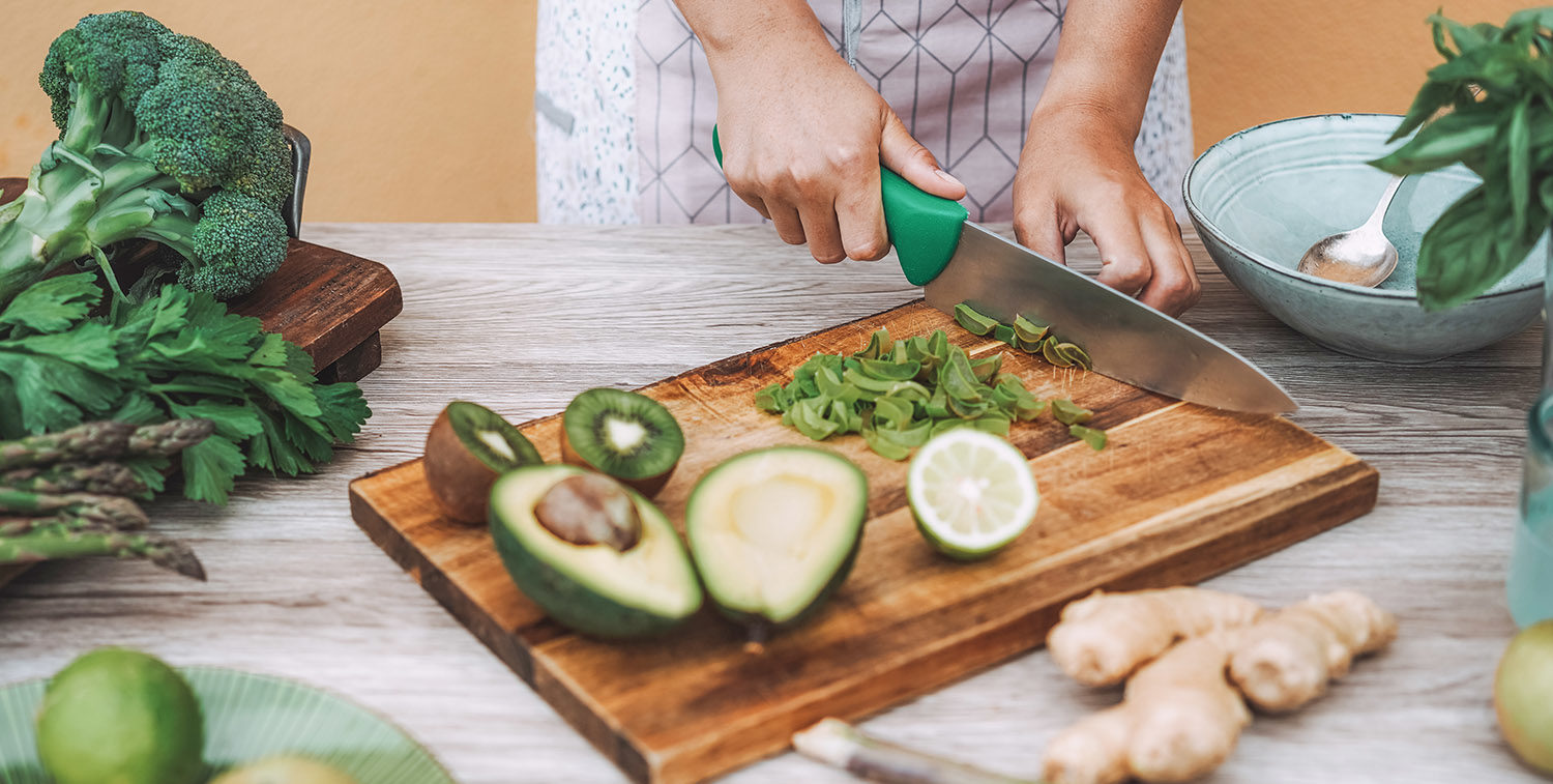 Young woman preparing detox juice - Girl making smoothie with green vegetables and fruit - Healthy lifestyle nutrition during isolation quarantine - Main focus on left hand